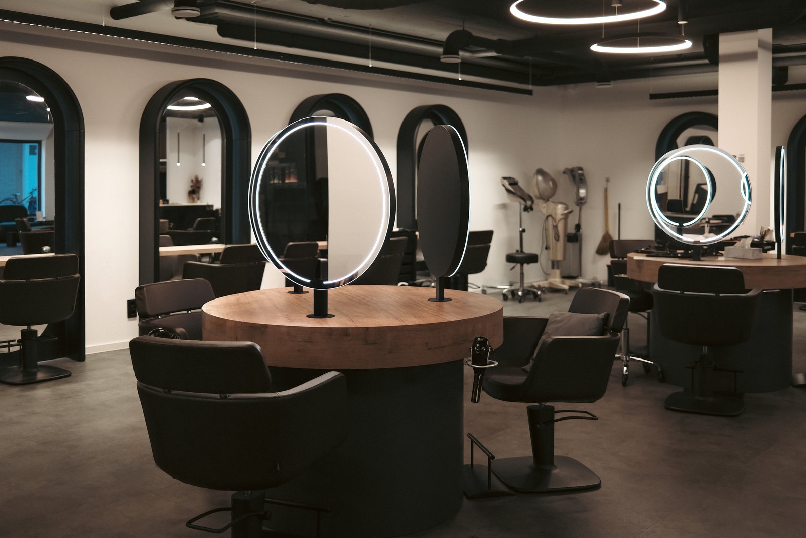Beyond Raum Oberursel — round styling stations with ring-light mirrors and arched wall mirrors